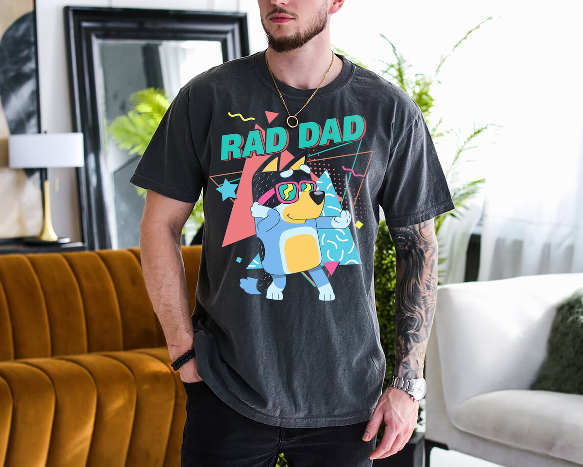 a man standing in a living room wearing a rad dad shirt